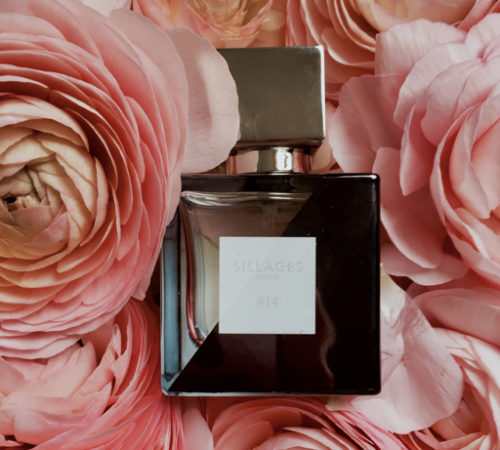 Un flacon 50ml de Sillages Paris, parfum personnalisé pour la fête des mères, posé sur un lit de pivoines rose pâle.